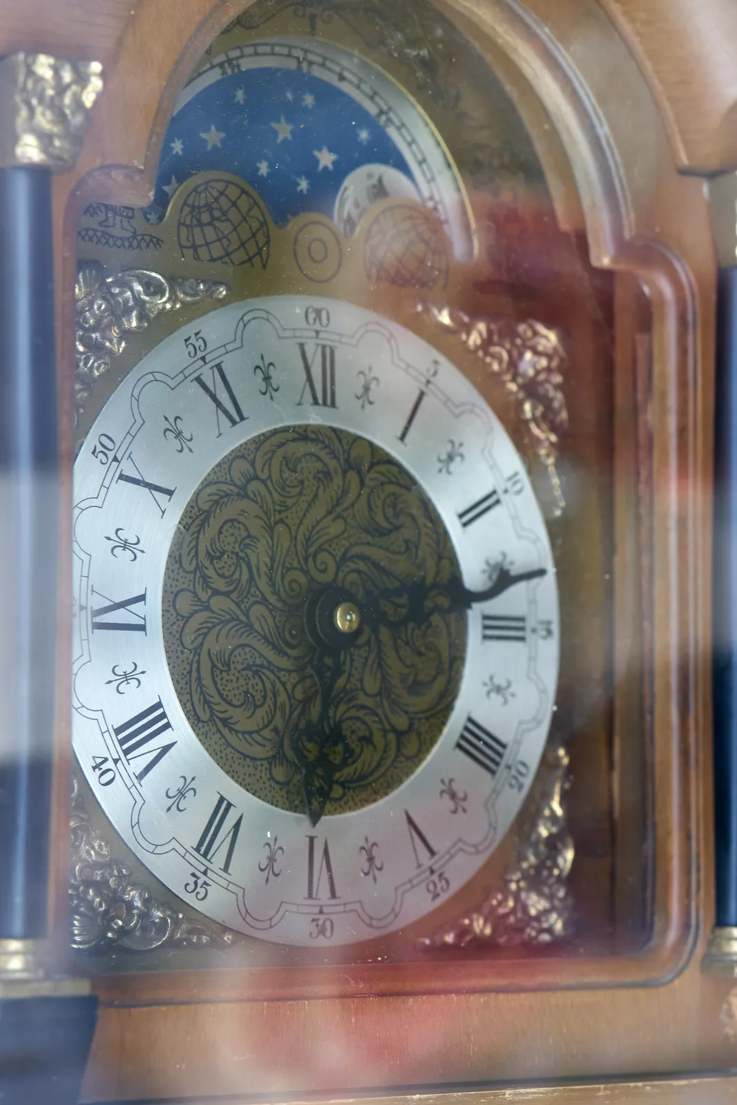 A detail of an old wooden clock. It points at 13 past six.