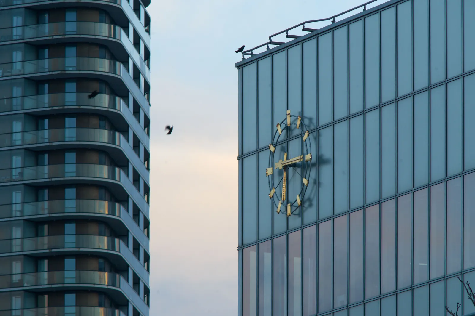 On this large clock, attached to a tall glass building, it is a quarter past six.