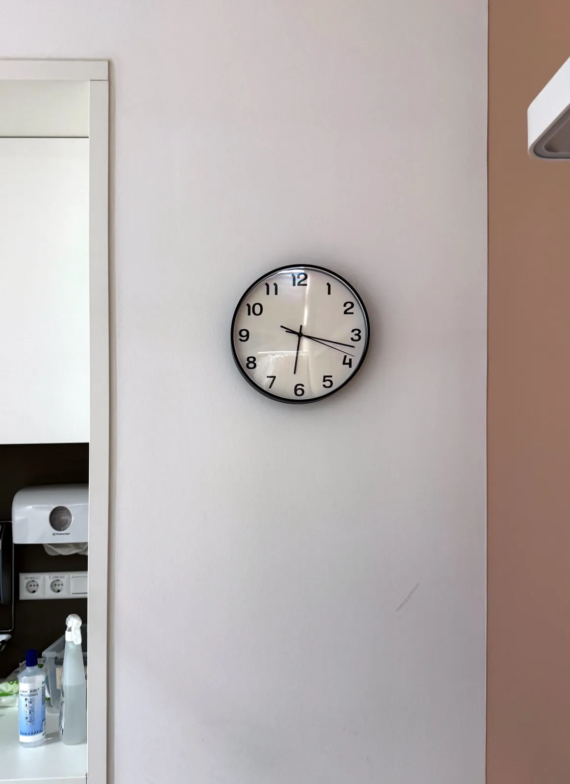A nice minimalist wall clock on a wall. It points at 16 minutes past six. 
