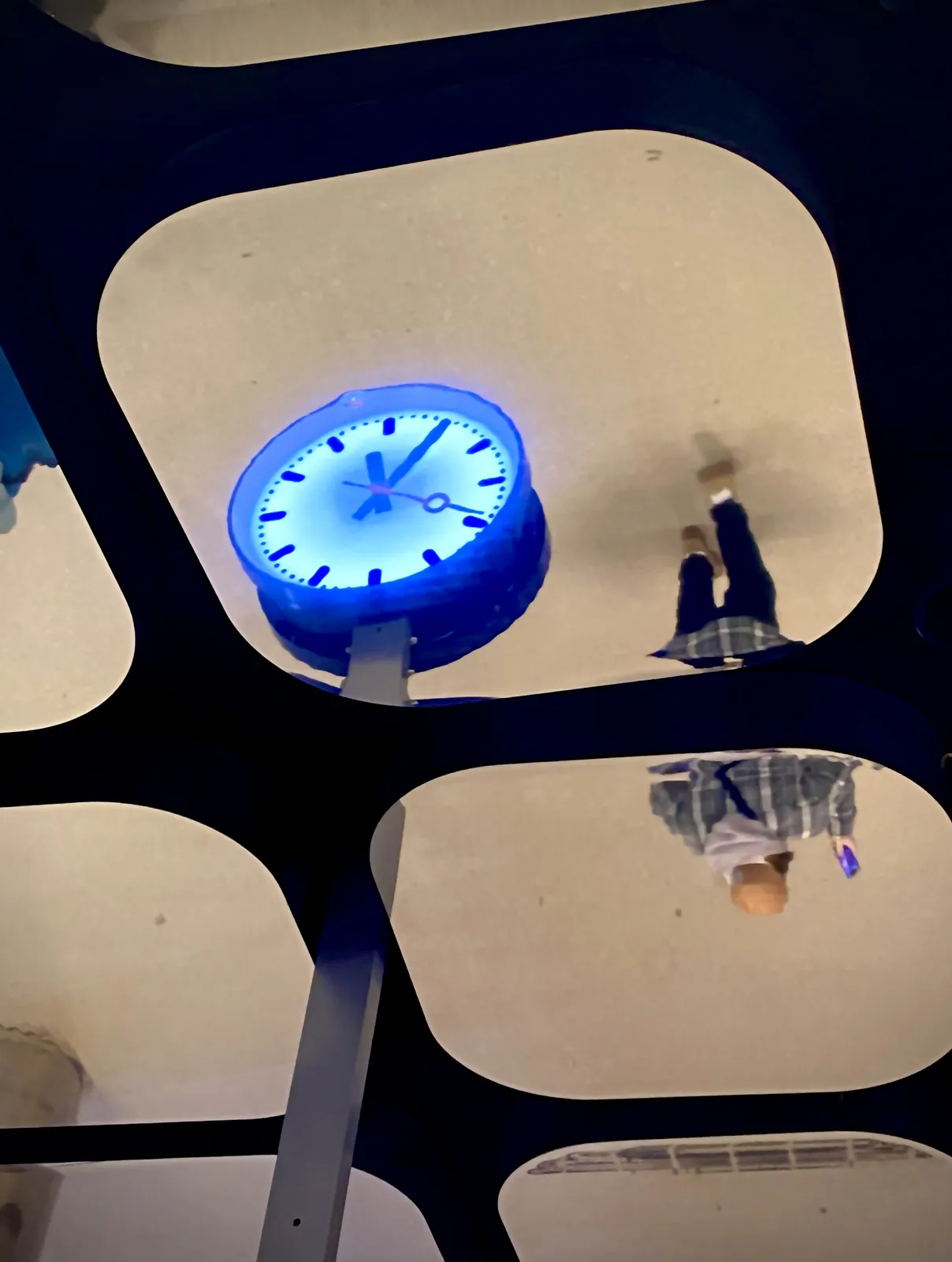 There are square mirrors with rounded corners on the ceiling. In one of these mirrors you can see a clock. Of course it’s a bit confusing and unclear what time this clock shows. But after some consideration you can conclude that it is 25 minutes past 6.