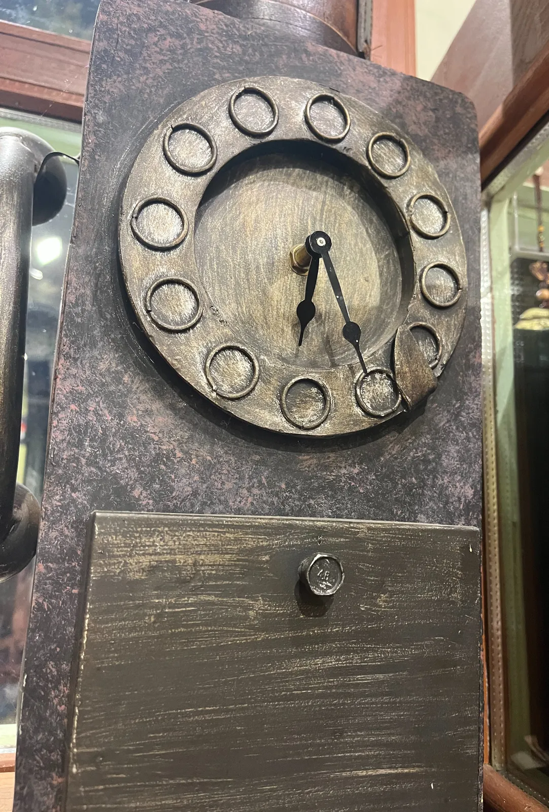 A box, painted to look like its some sort of corroding metal, mith a clock on it. It points at 25 minutes past 6.