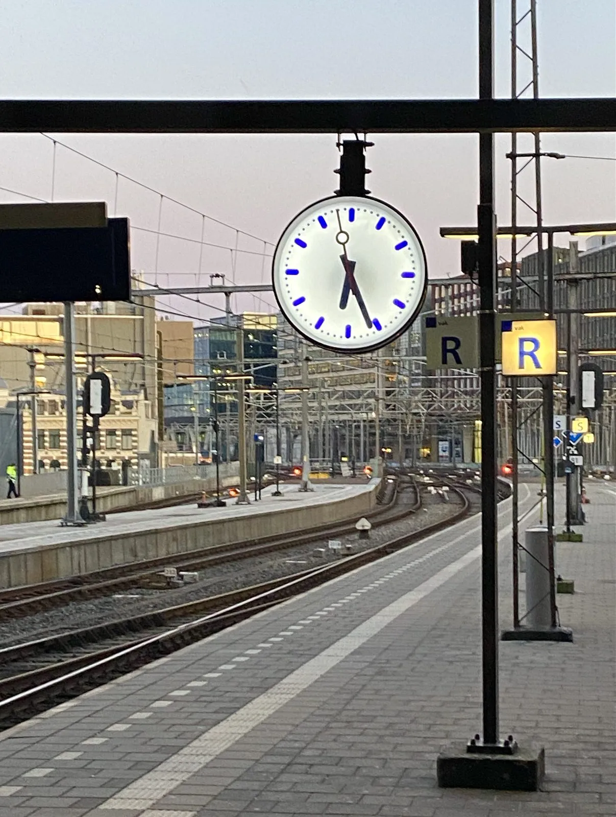 This clock on a platform of a large train station points at 26 past 6.