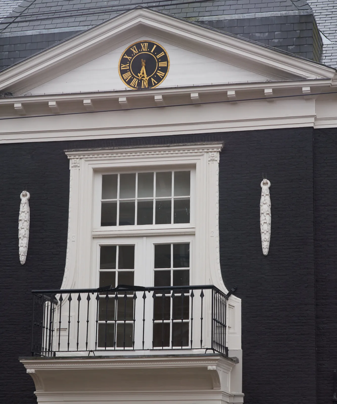 A clock in the facade of a classic building points at 28 past six. 