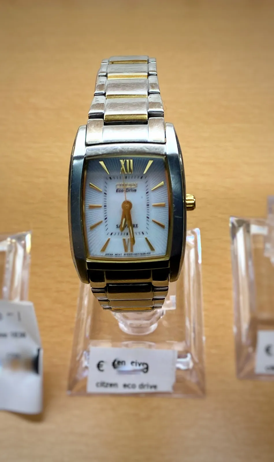 A Citizen Eco-Drive watch. It points at 29 minutes past 6.