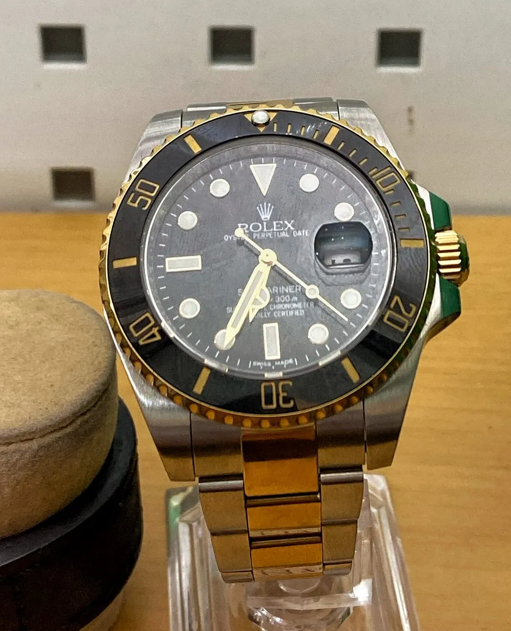 A Rolex Oyster Perpetual Date watch. It points at 26 minutes to 7.