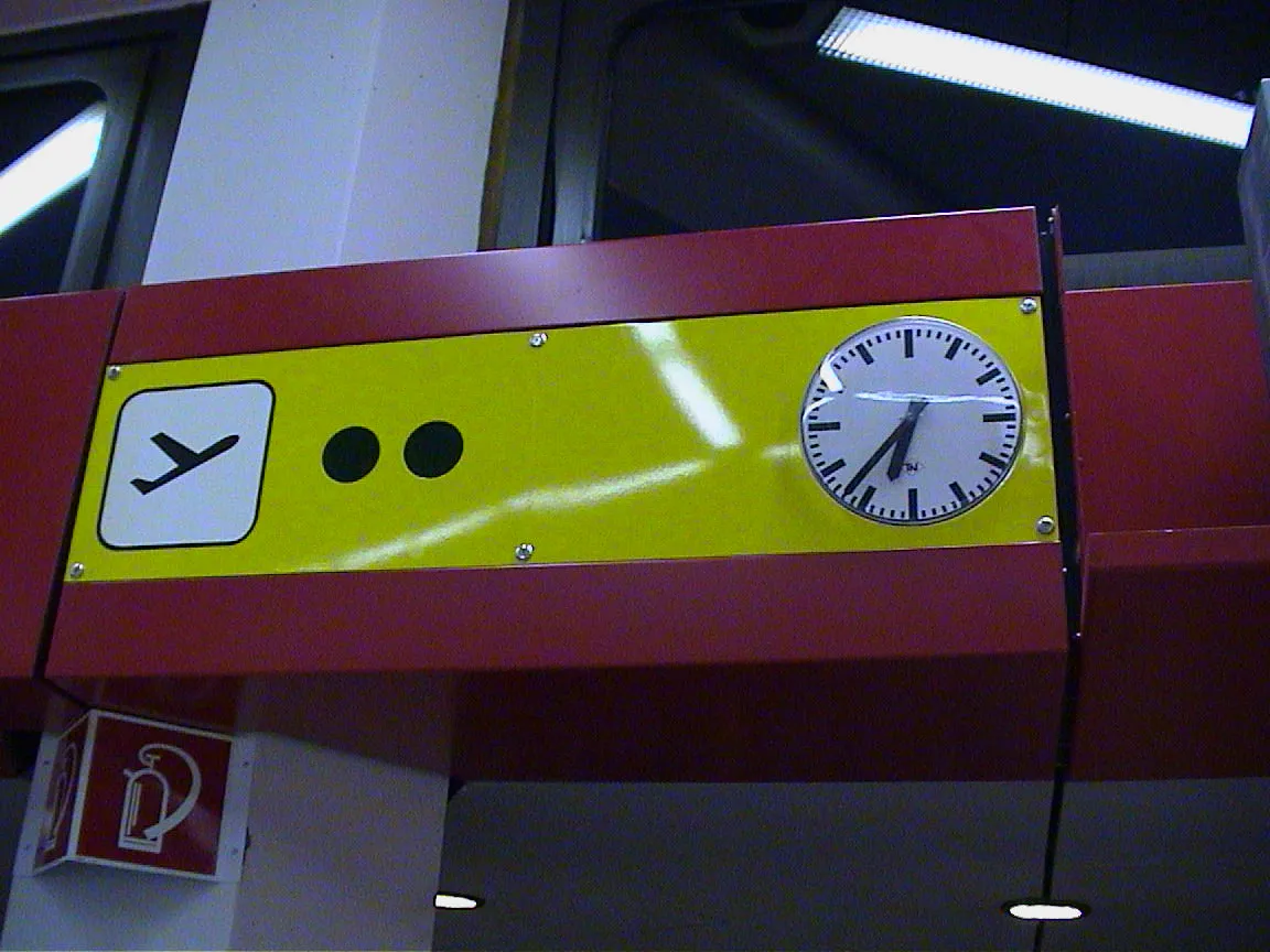 A clock on an airport says it is thirty seven past six.