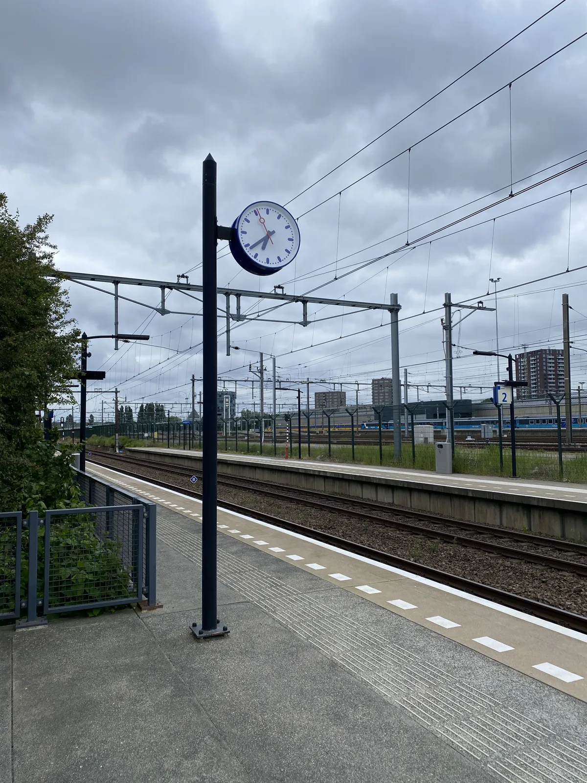On a train station somewhere in the Netherlands there’s a clock on a pole. It points at 22 minutes to 7.