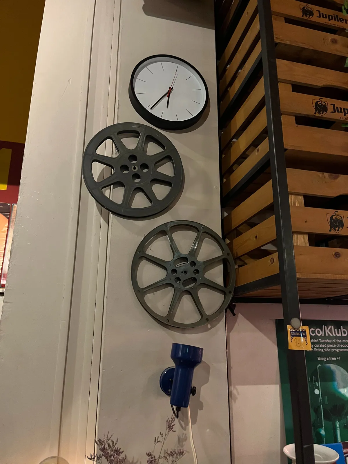 Some film reels and a clock on a wall. It points at 21 minutes to 7.