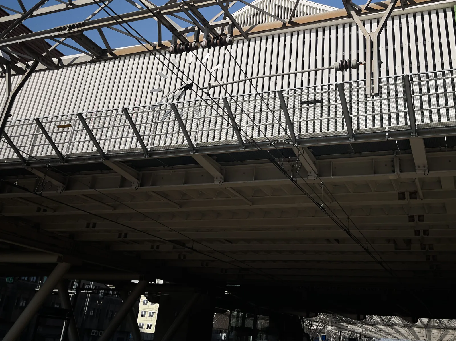 A monumental roof, covering a train station. There’s a large clock built into this roof, which points at 19 minutes to 7.