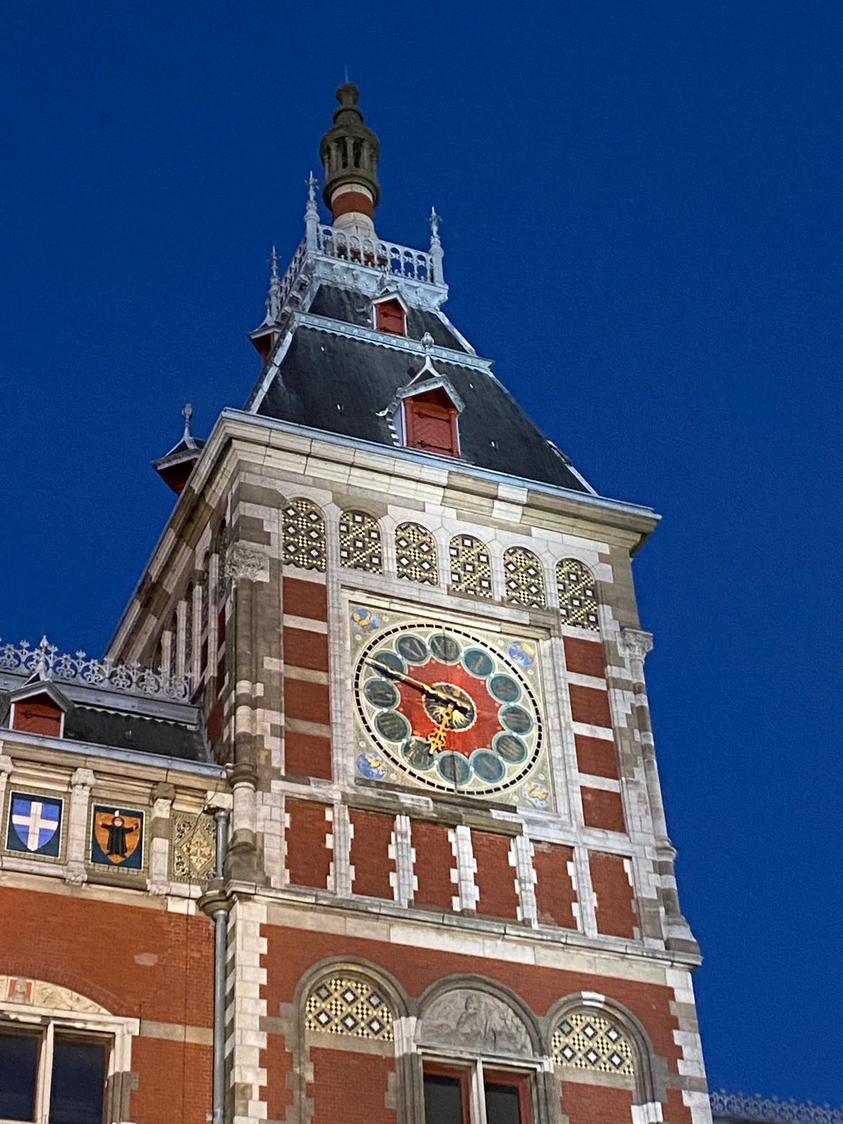 The clock on the ornamented tower of Amsterdam central station points at 11 to 7.