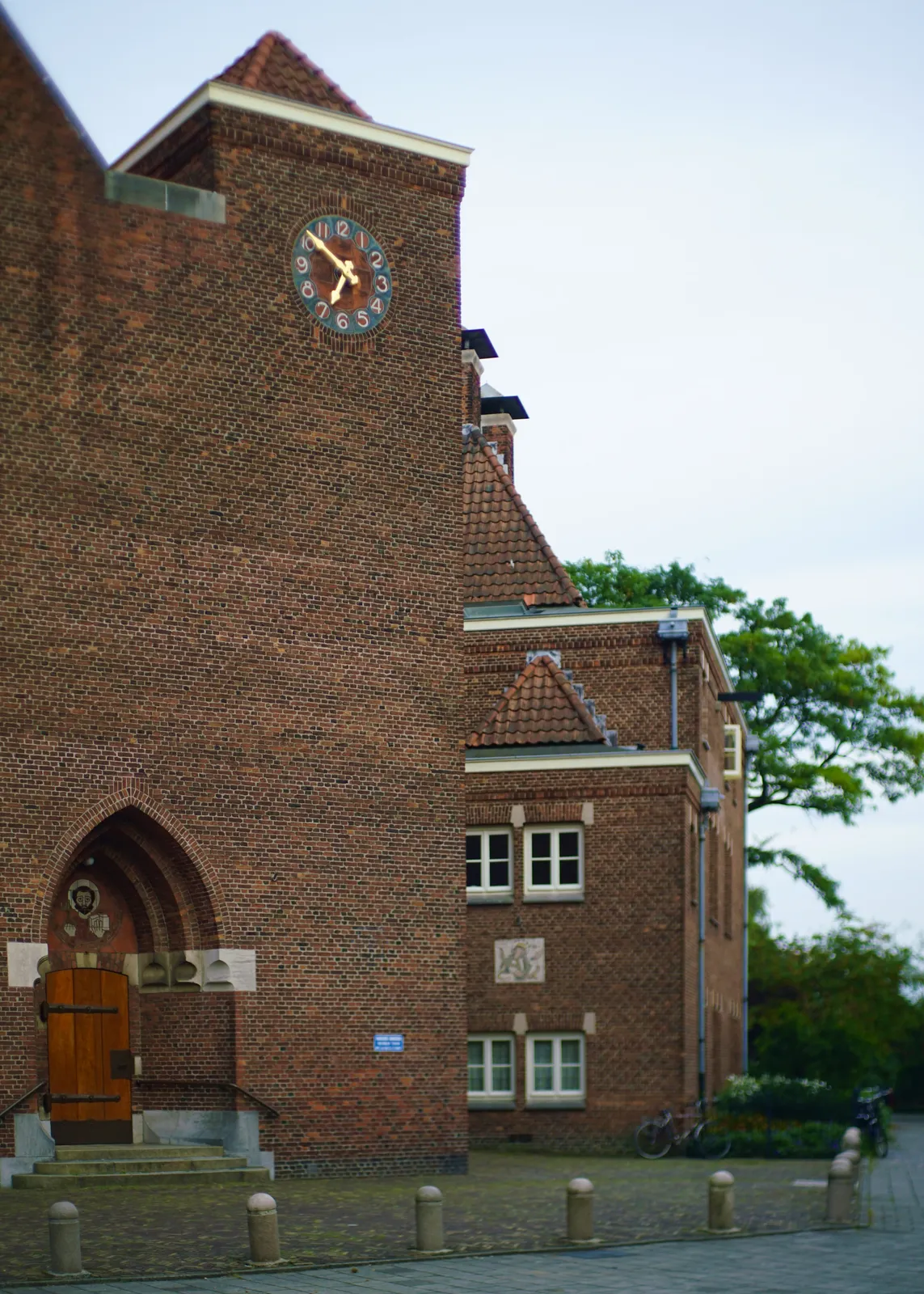 This church has a very bricky facade. On this facade there’s a clock. It points at 9 minutes to 7.
