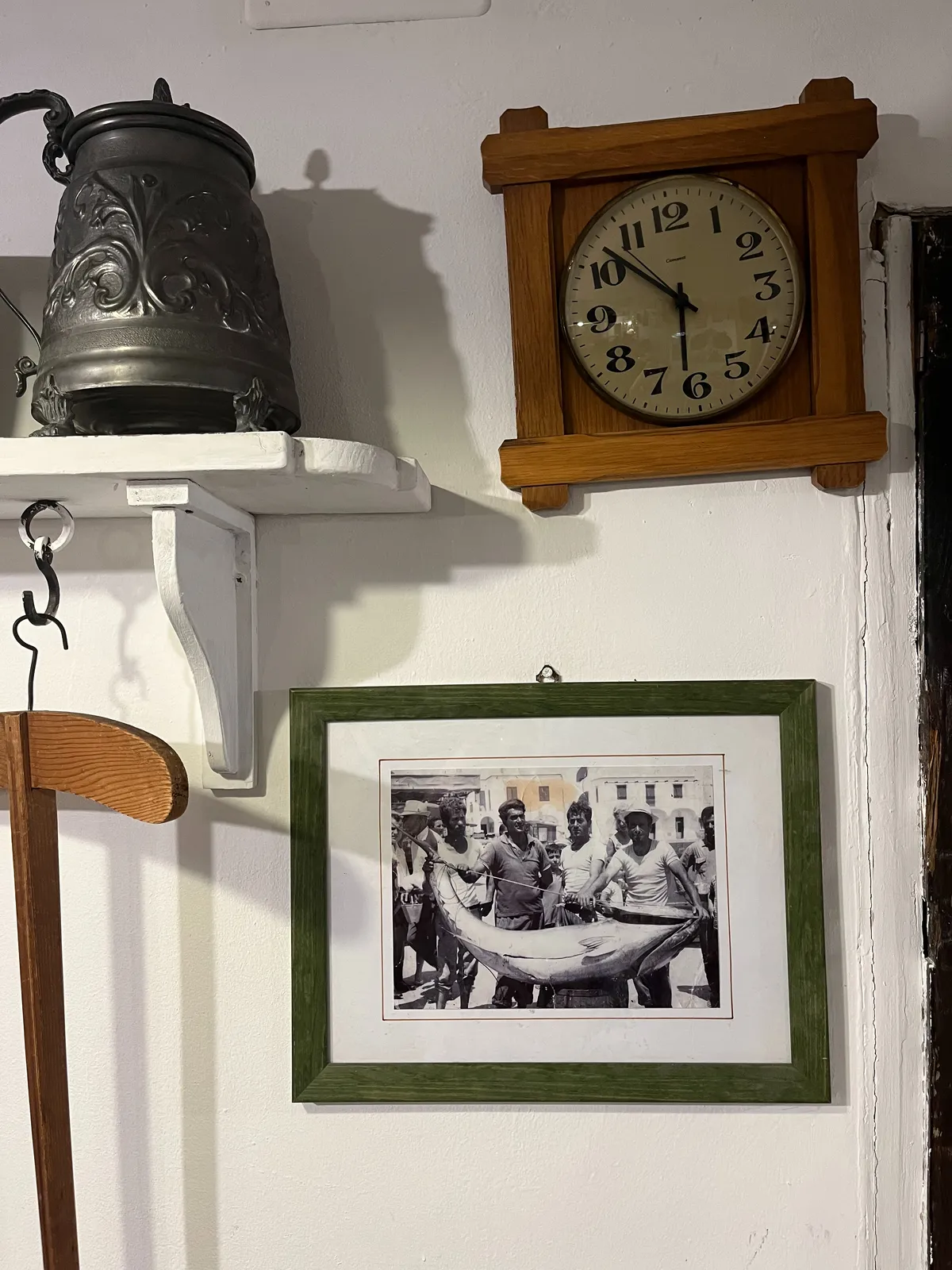 On a wall there’s an old picture of fishermen who caught a very large fish. There’s also a brass bell and a clock that points at 8 minutes to 7.