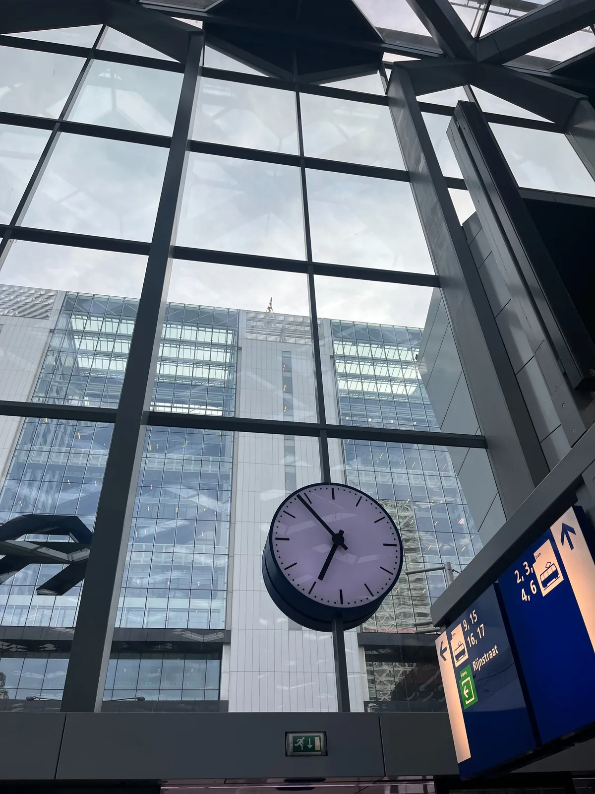 A clock built into a huge glass facade. It points at 6 minutes to 7.