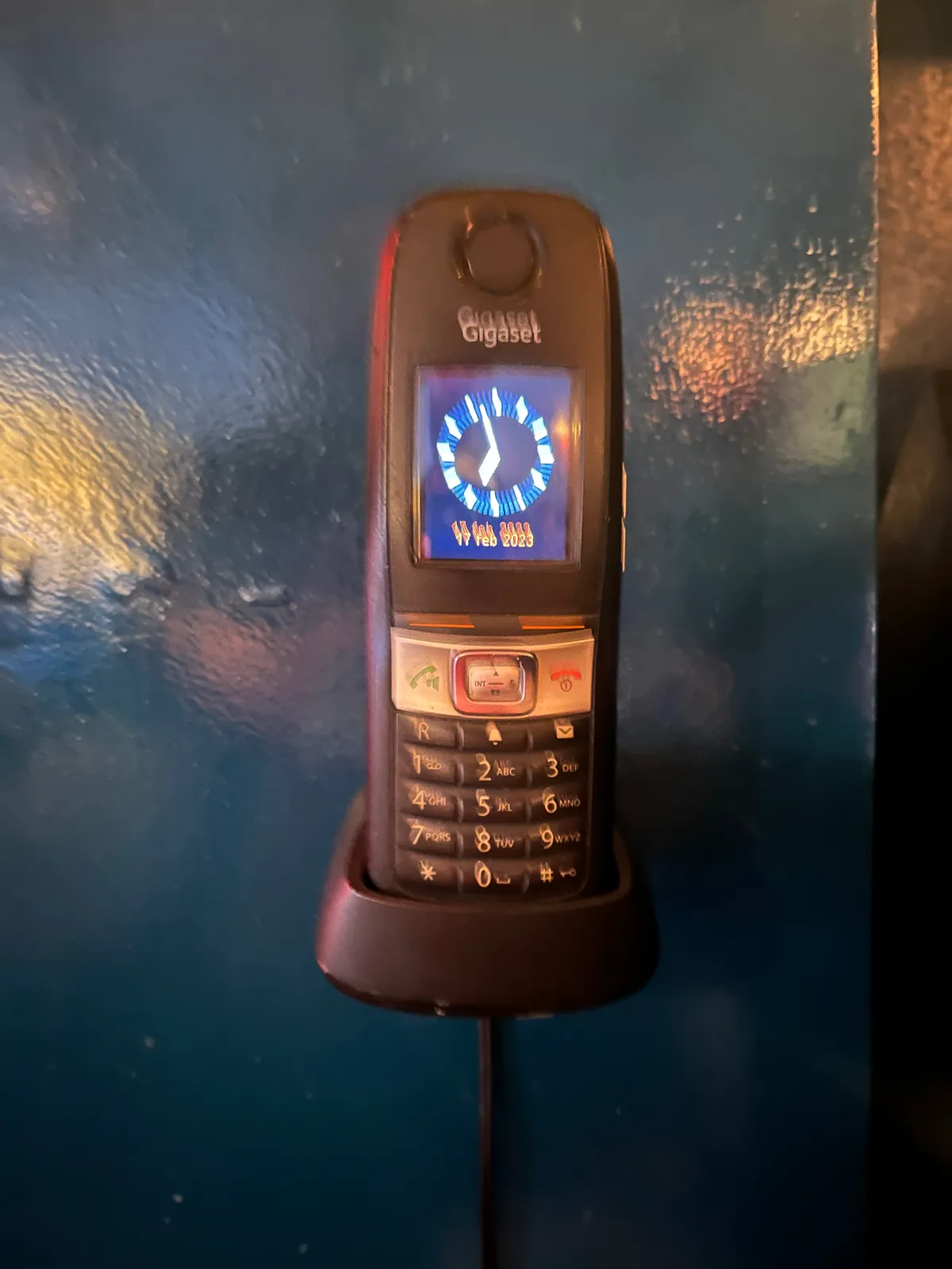 A clock on a telephone points at three minutes to seven.