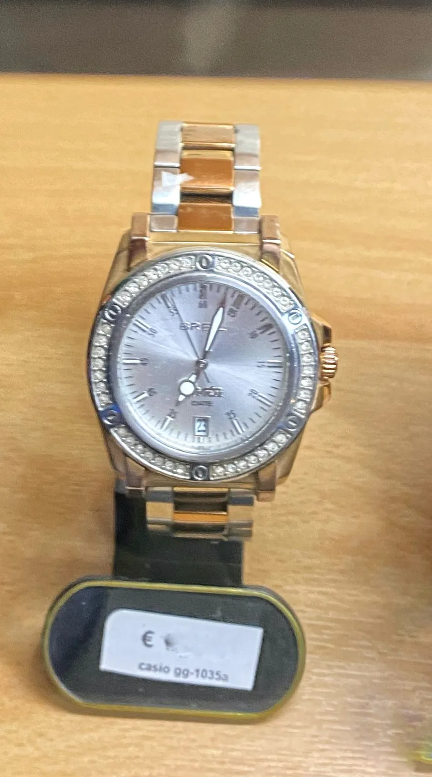 A shiny wrist watch. It points at 3 past 7.