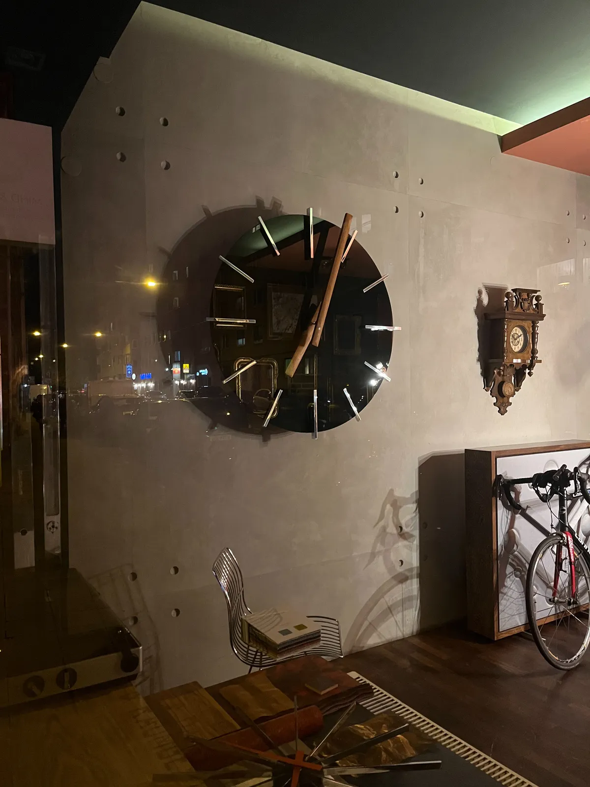 An enormous clock on a wall in a design shop. It points at 4 minutes past 7.
