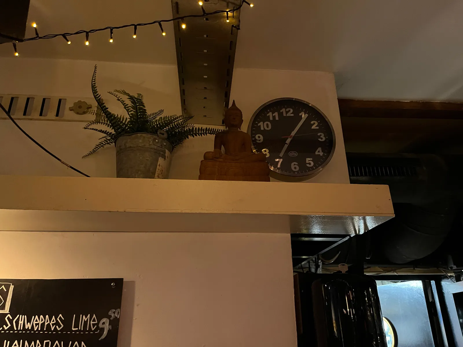 Next to a plant and a buddha, there’s a clock that points at six minutes past 7.