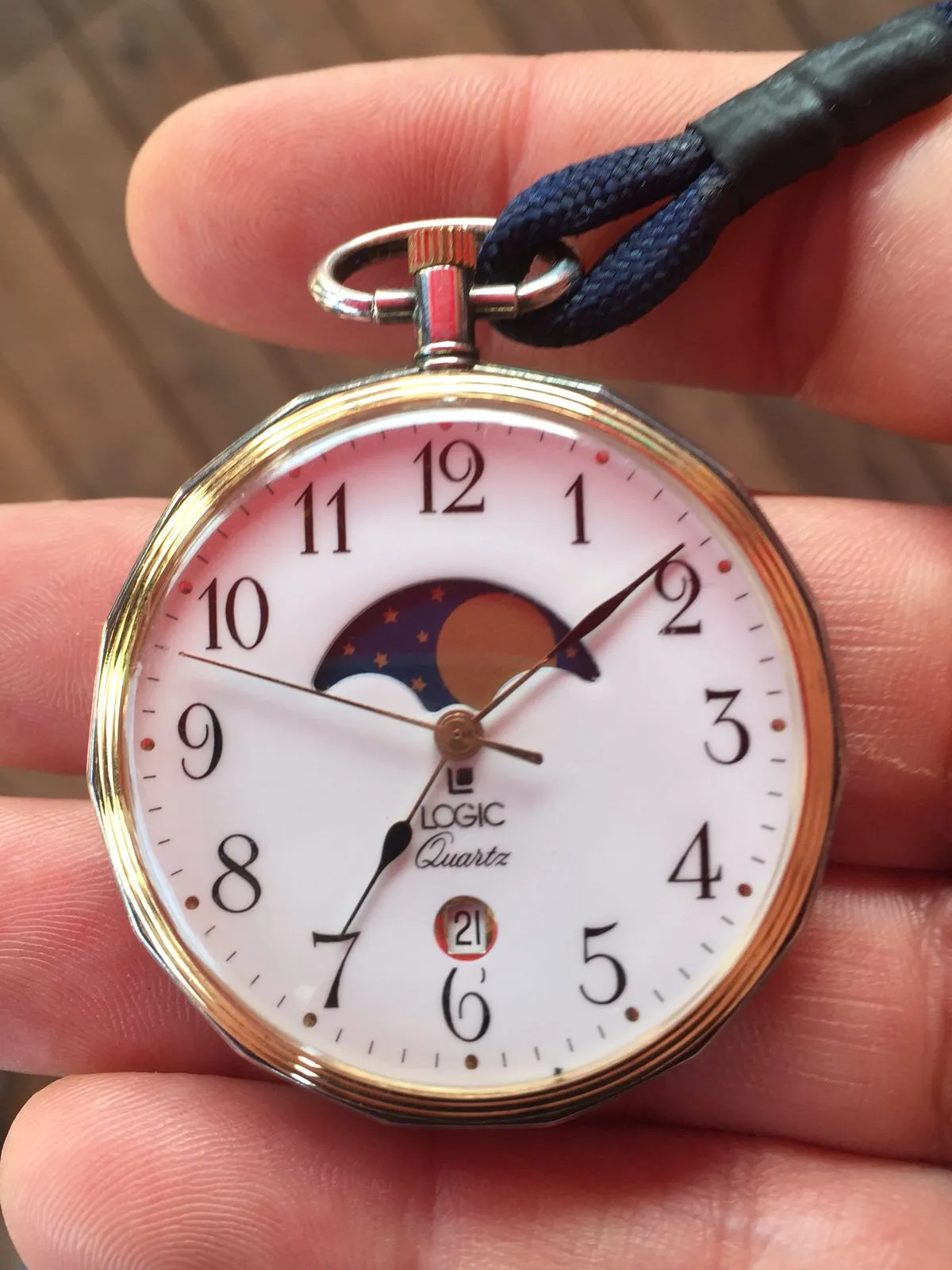 Someone is holding a watch in their hand which points at eight past seven.