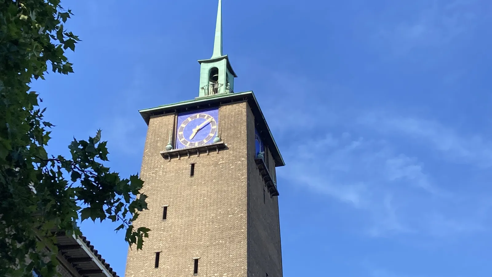 A church tower with a brass spike on top. It also has a clock that points at 9 past 5.