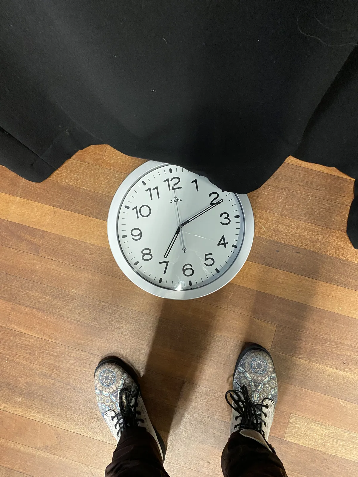 Looking down at the floor you can see the legs and the — beautifully decorated — shoes of the photographer. There’s also a clock on the floor. It points at 11 past 7.