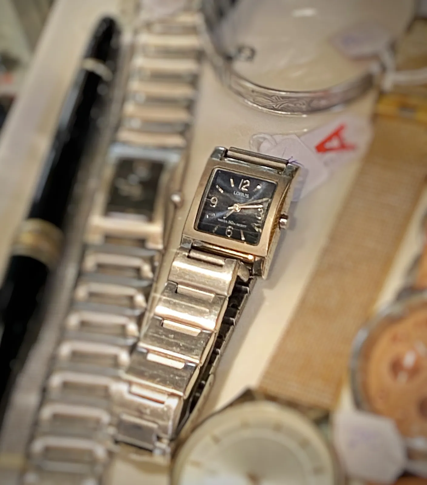 A tiny silver wrist watch. It points at 13 past 7.