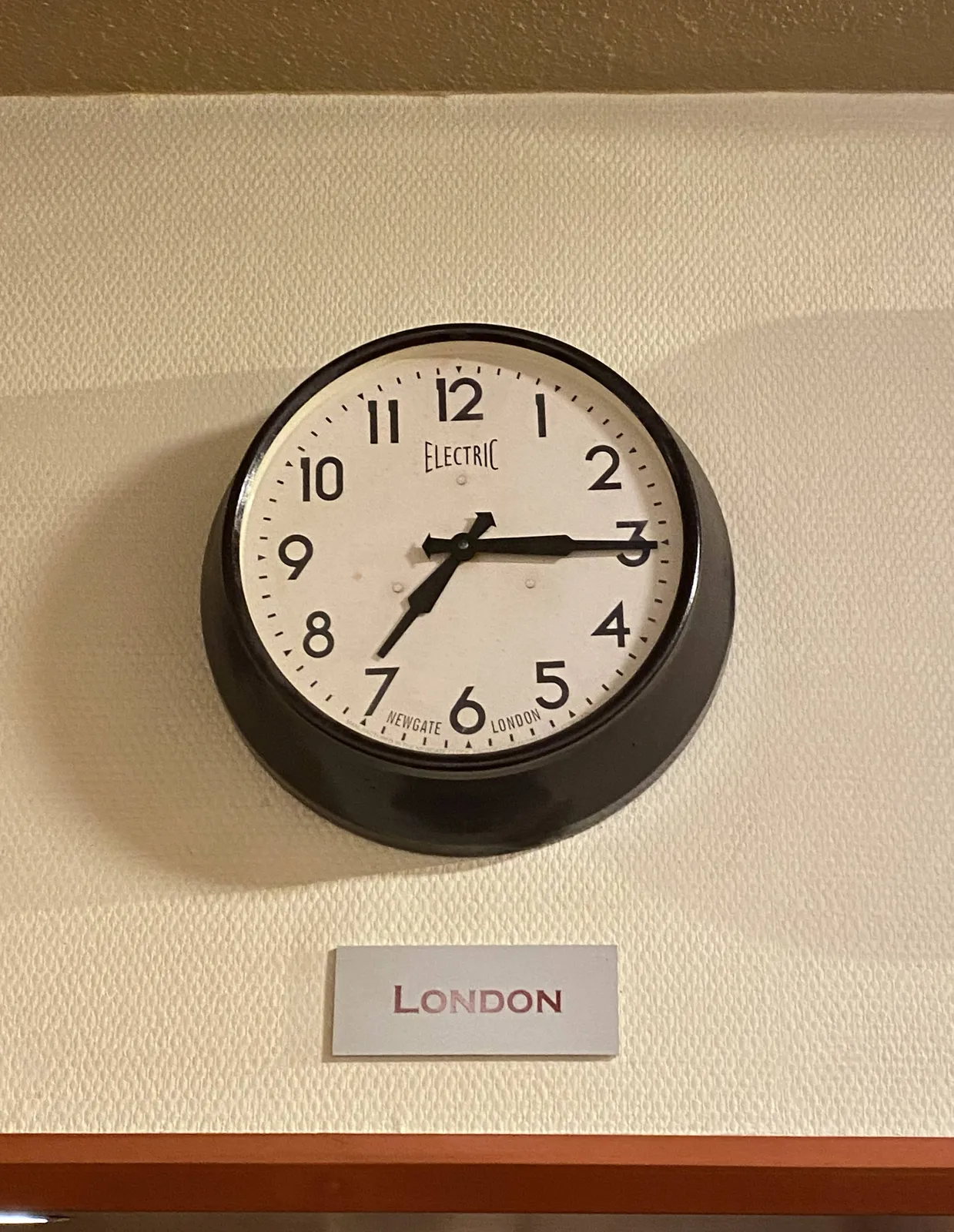 A sign that says that this clock shows the time in London. According to this clock it is a quarter past 7.