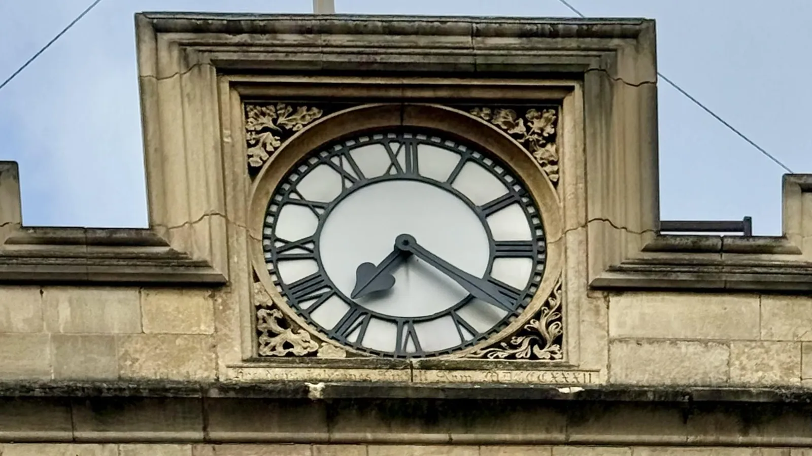 A clock built into a tile on a roof. It points at 21 minutes past 7.