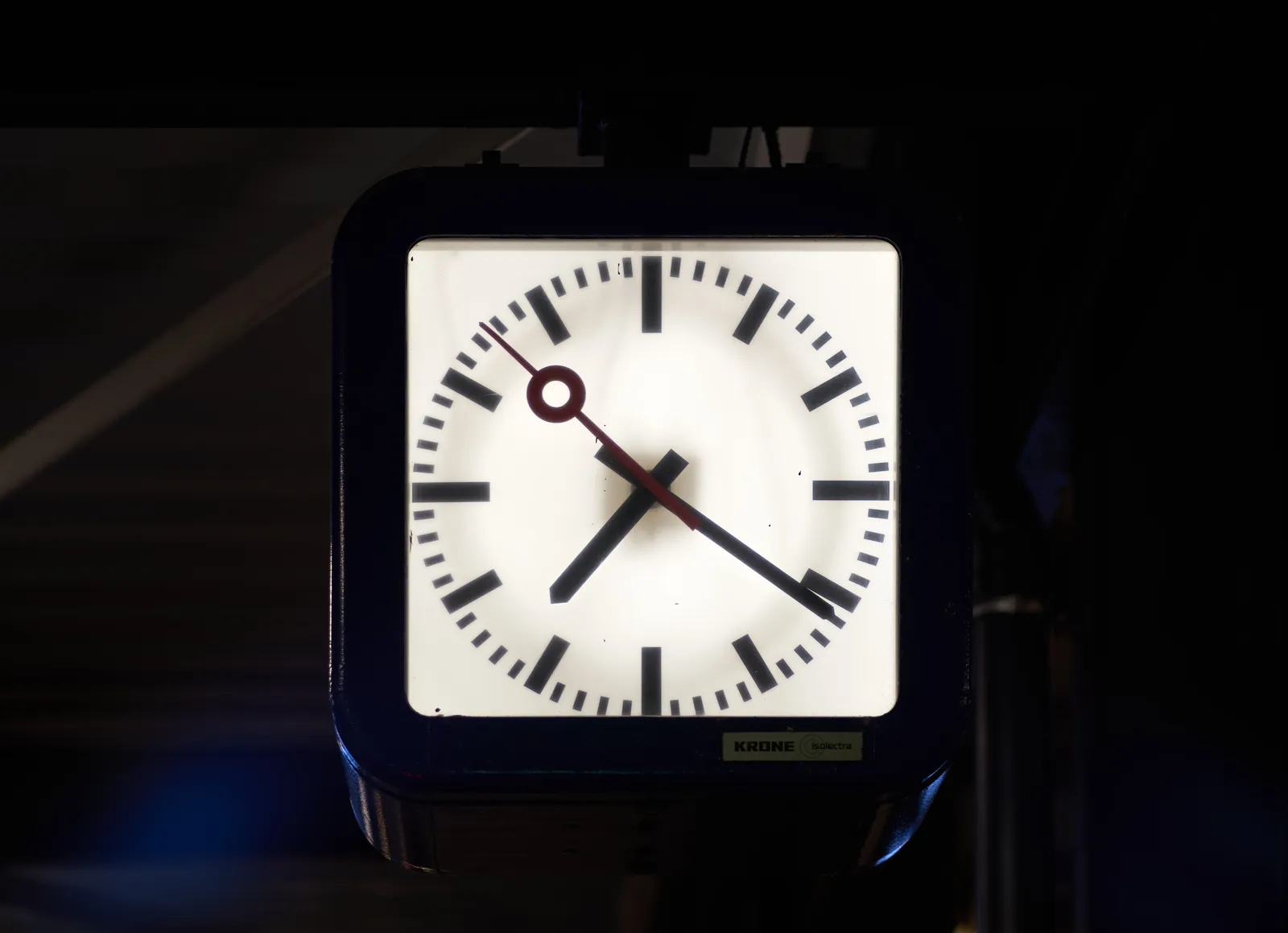 A modernist station clock points at 21 past 7.