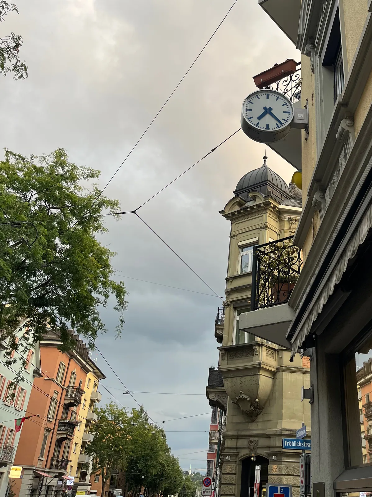 Attached high up to an old building is a clock. It points at 23 past 7.
