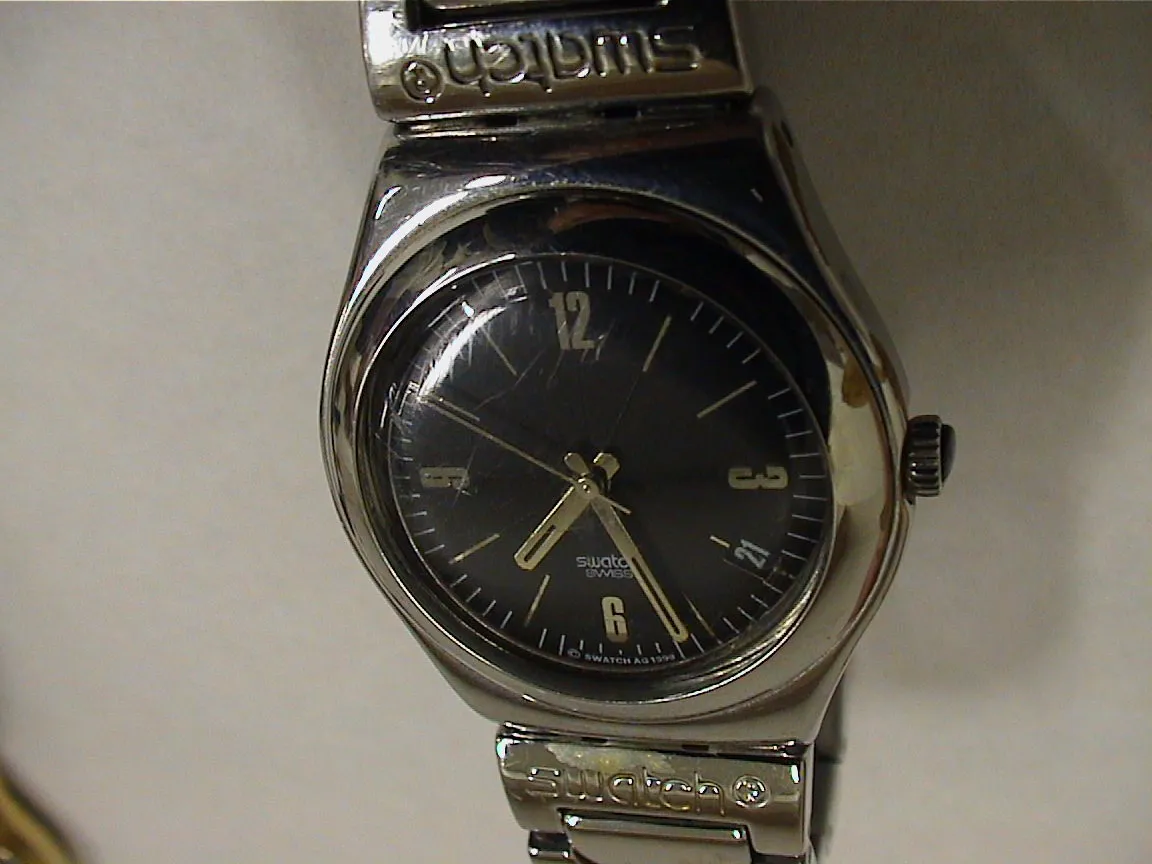 A silver watch points at twenty six past seven