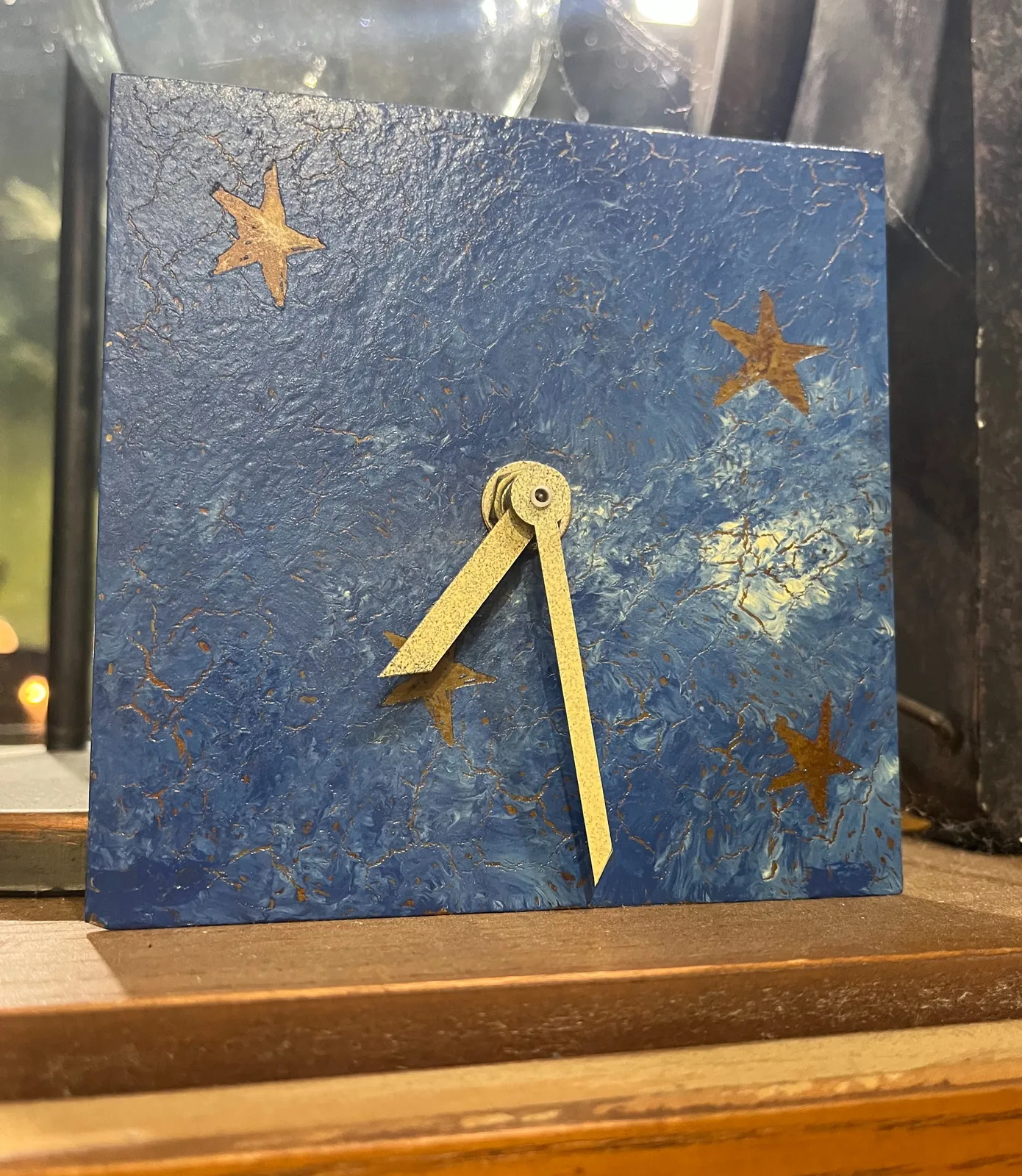 A clock with golden stars painted on it, and golden hands. The hands points at approximately 29 minutes past 7.