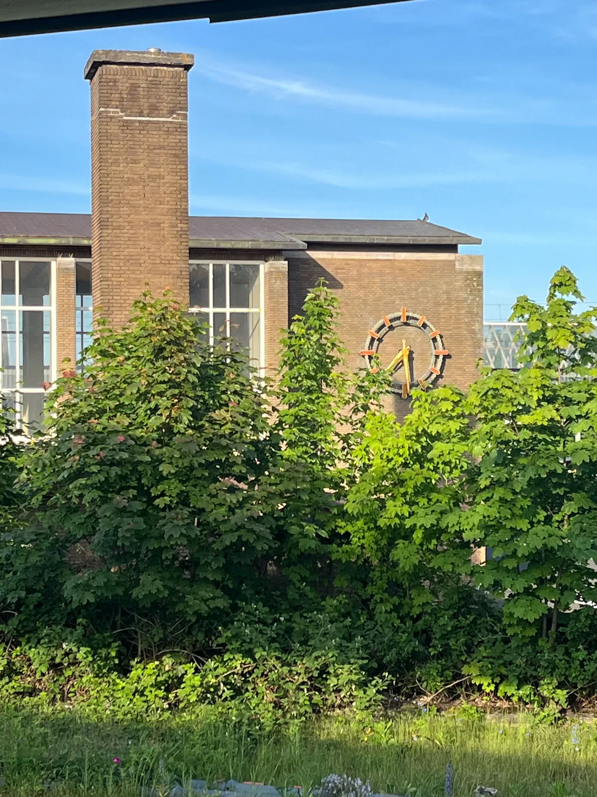 The large station clock of the Amsterdam Muiderpoort station, on a bright sunny day, points at 29 minutes past 7.
