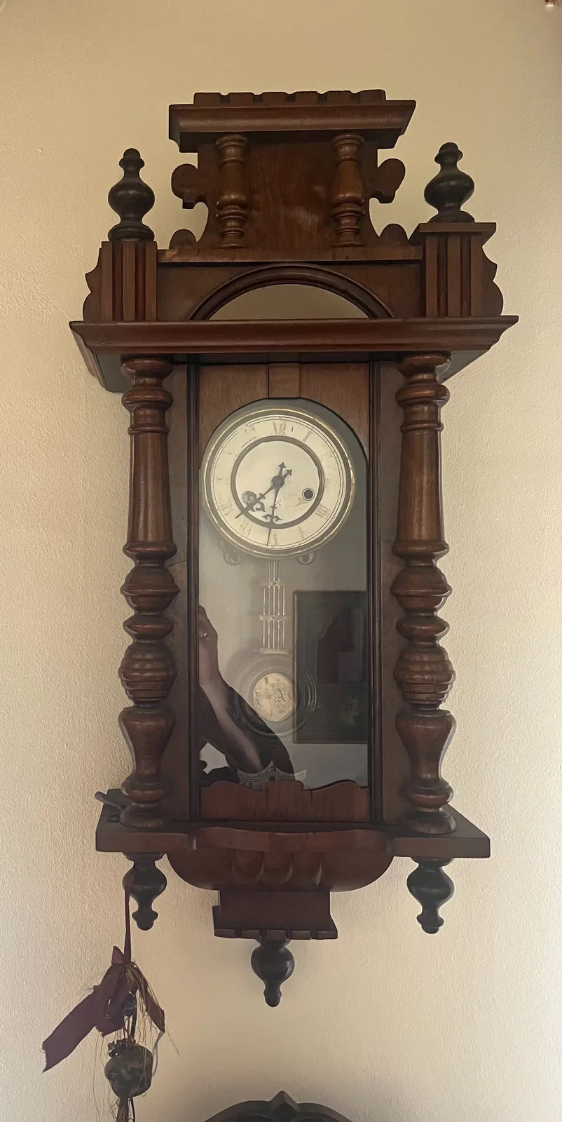 An antique looking, dark wooden clock, with quite some ornaments. It points at half past seven.