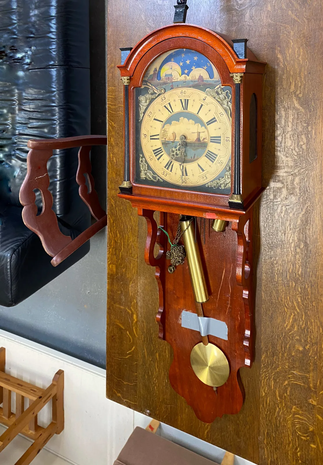An old, wooden wall clock with things painted on it. It points at half past 7.
