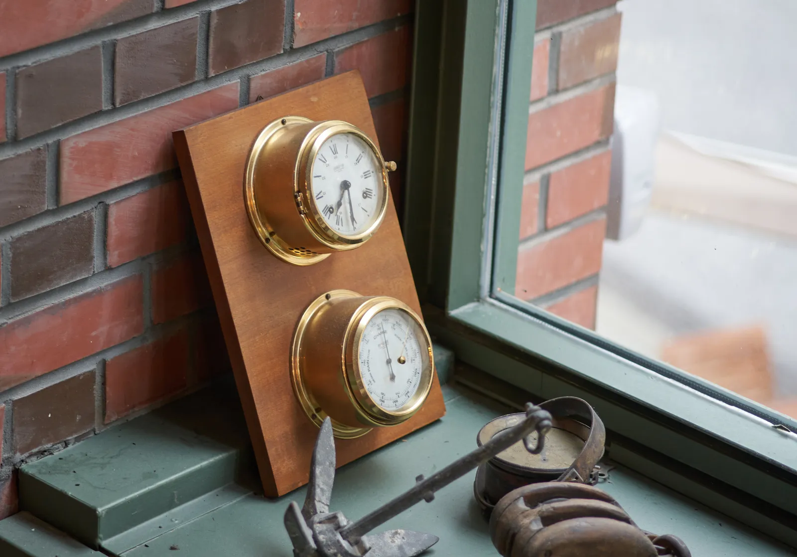 Some old maritime stuff and a barometer and a clock attached to a piece of wood. The clock indicates that it is 29 minutes to 8.