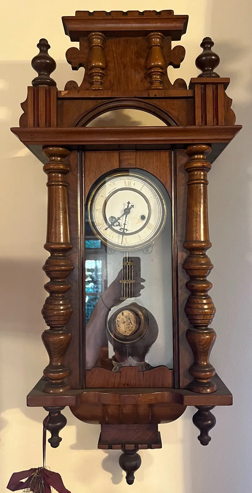 An old wooden clock. In the reflection in the glass in front of the pendulum you can see the hand of the photographer with the phone that’s taking this picture. On the clock it’s 31 past 7.