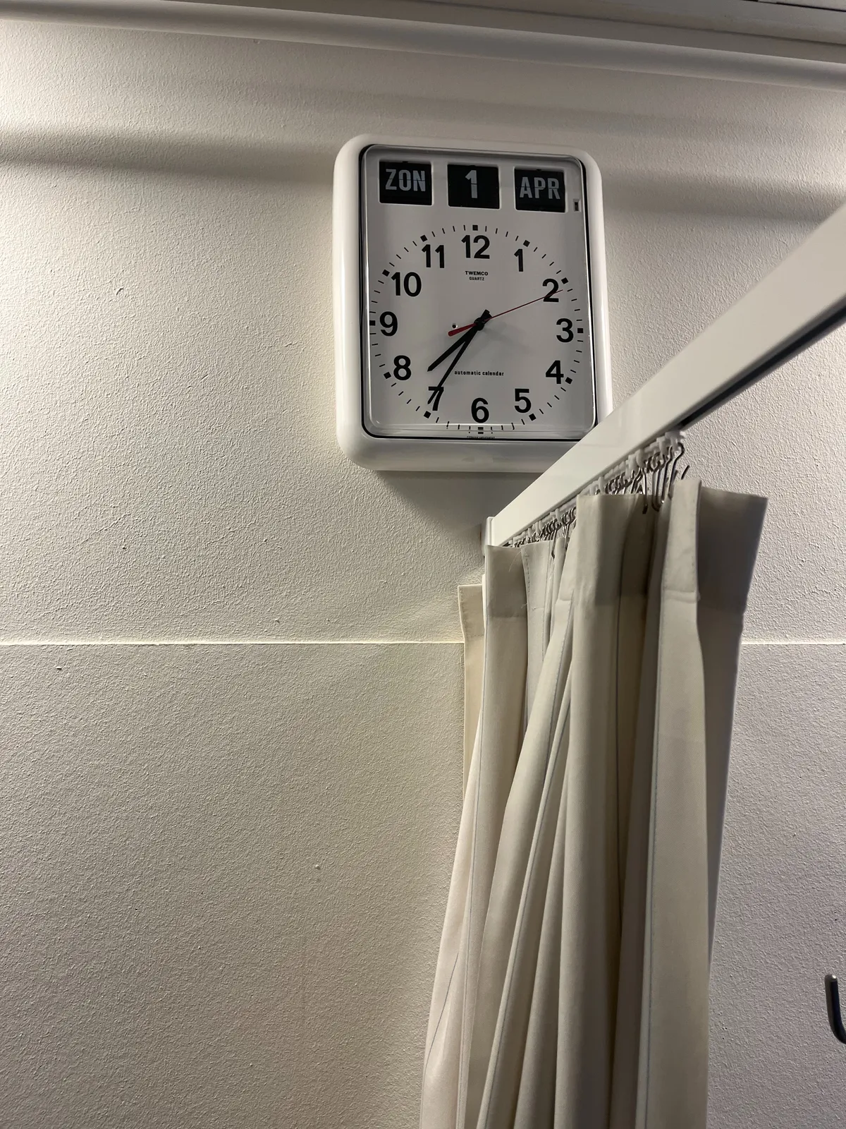 A clock with the date on it. The date says it is Sunday the first of April (which it wasn’t on the day the picture was taken). The clock points at 25 minutes to 8. 