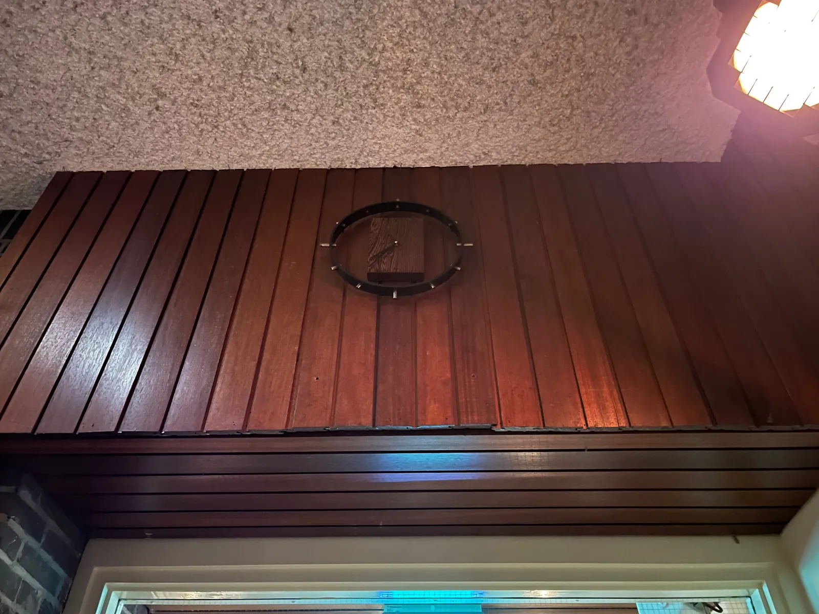 On this dark wooden panel there’s a clock made out of a wooden block and a little bit of black metal (an mostly empty space, really) it is 36 past seven.