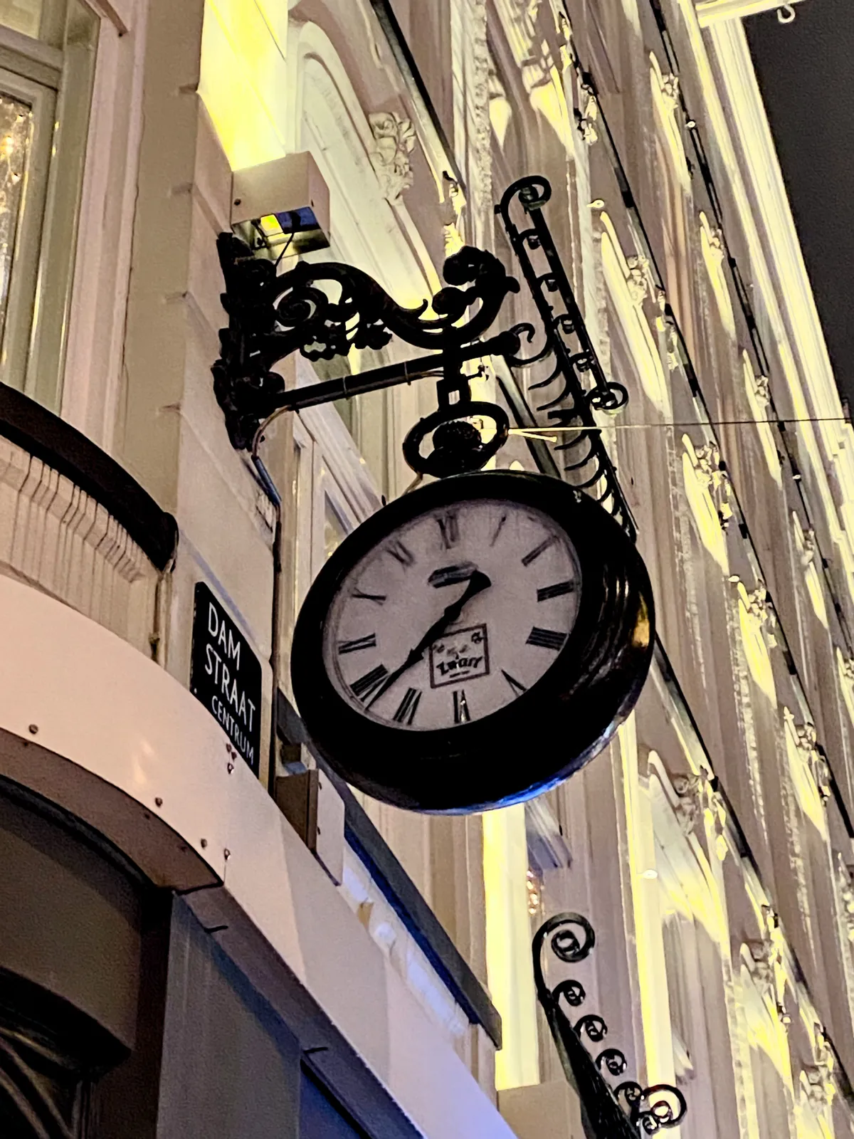 A large clock attached to a rather old and posh facade. It points at 22 minutes to 8.