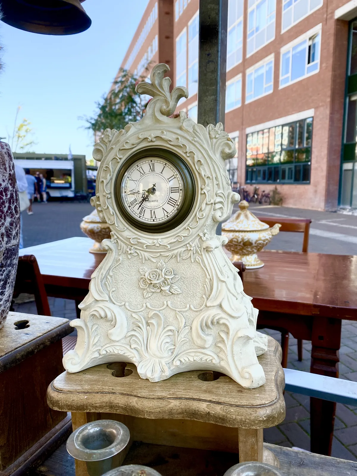 A white, richly ornamented clock. It points at 16 minutes to 8.