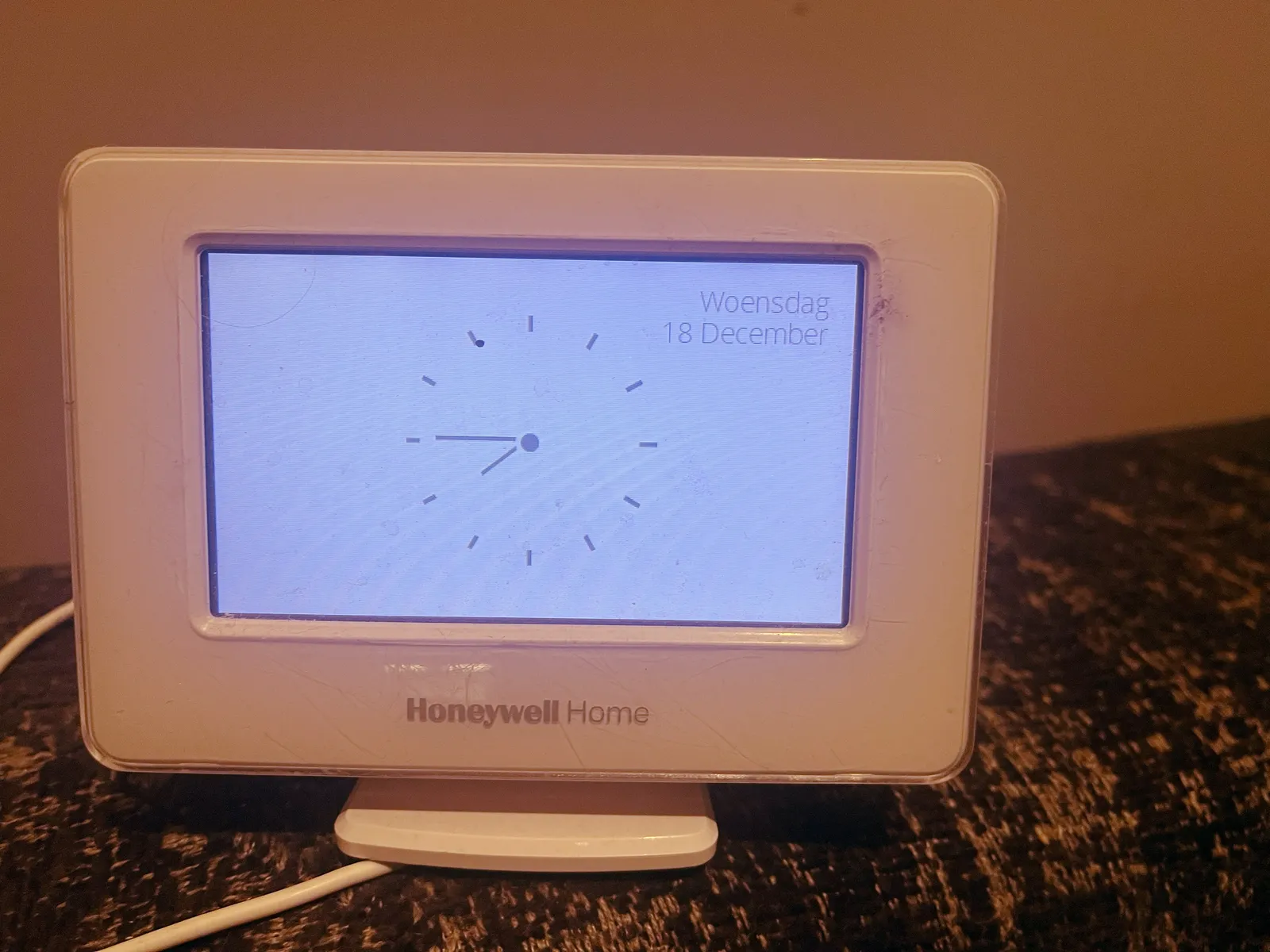 A honeywell home device says that it is Wednesday, the 18th of December. There‘s a large clock on its screen as well which points at a quarter to 8.