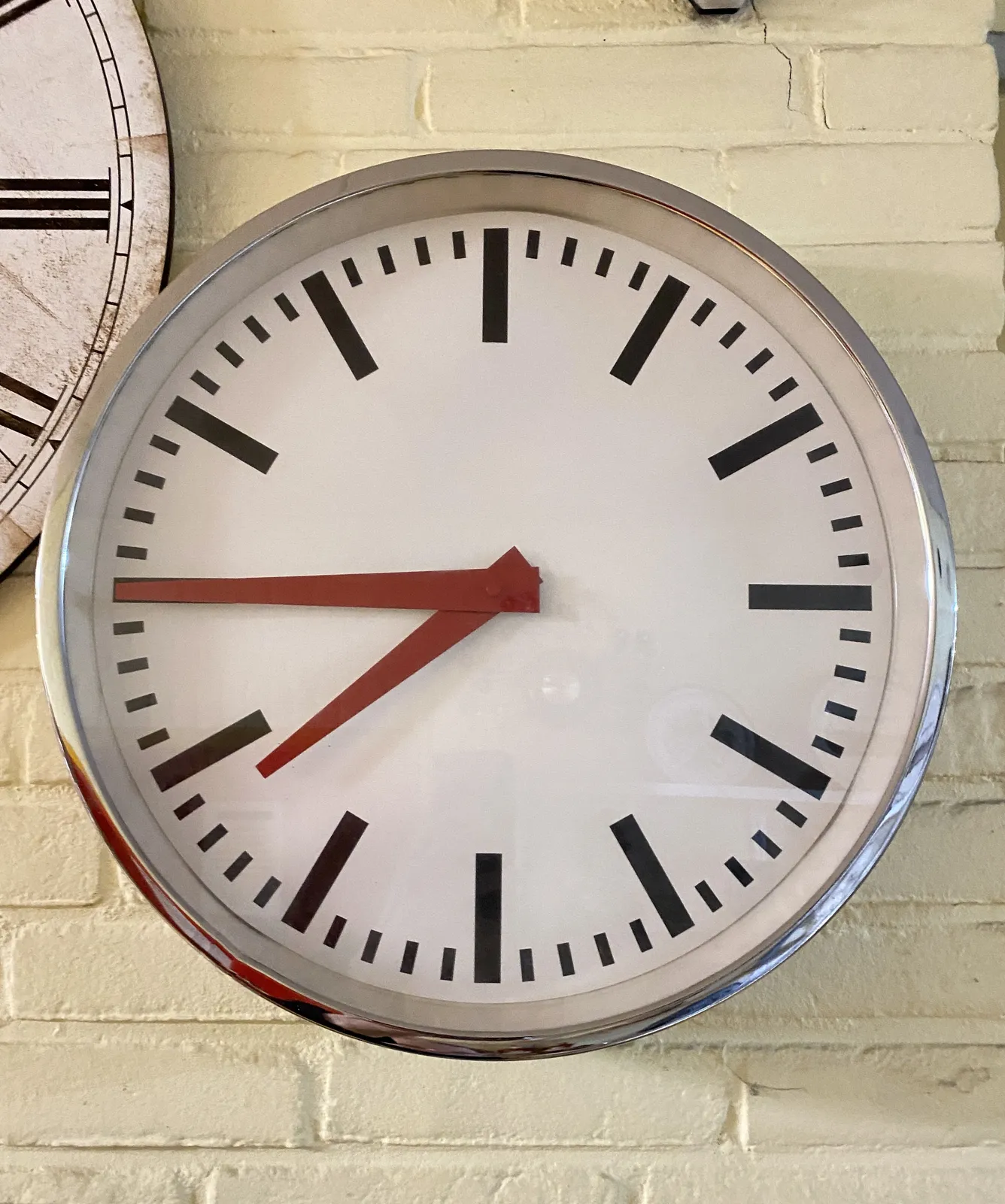 A modernist clock with — shocking! — red hands! It points at a quarter to 8.