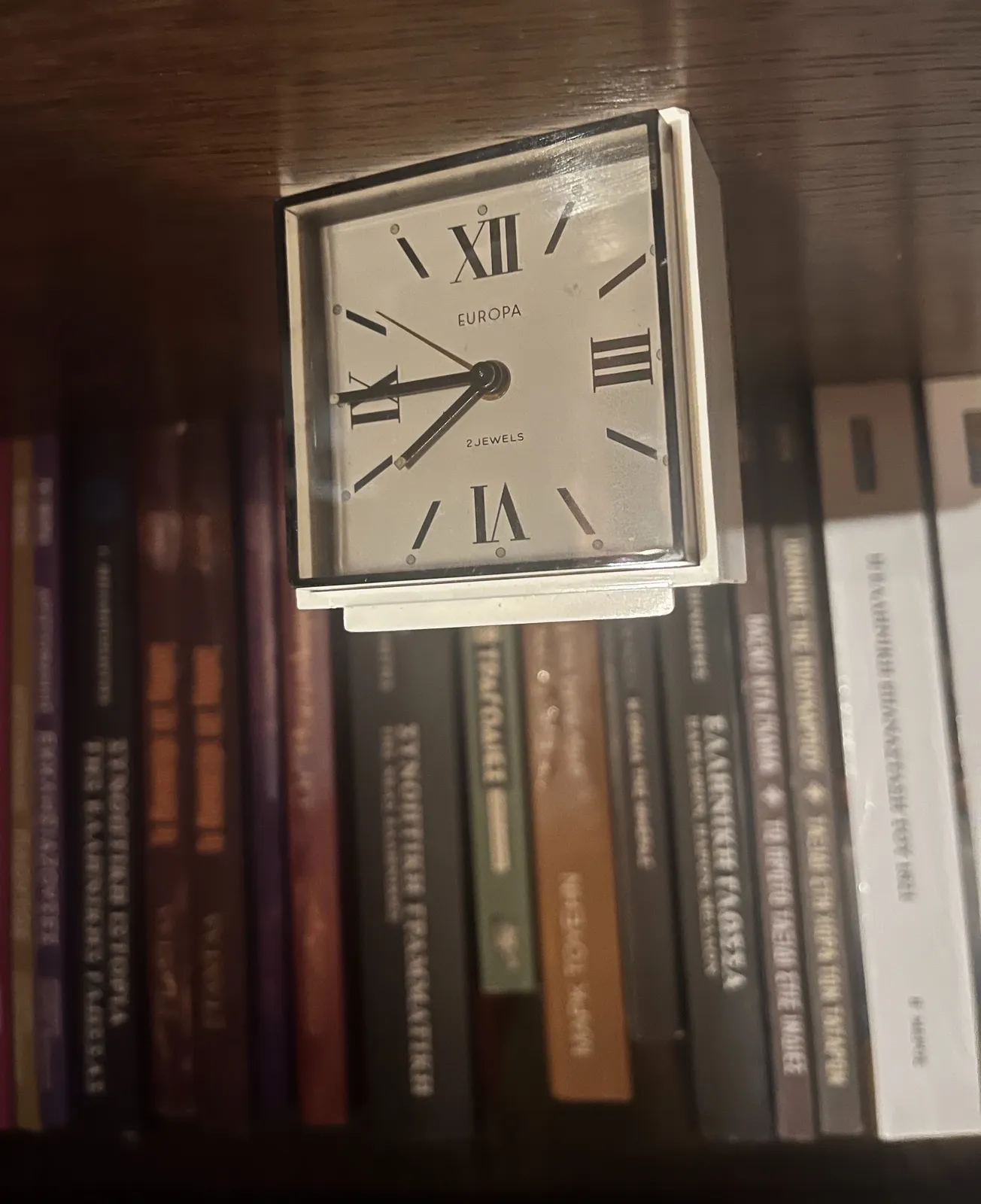This picture is upside down, because the clock on it was placed upside down on a shelf in front of some books. By turning the picture it is now much easier to read that it is a quarter to eight.