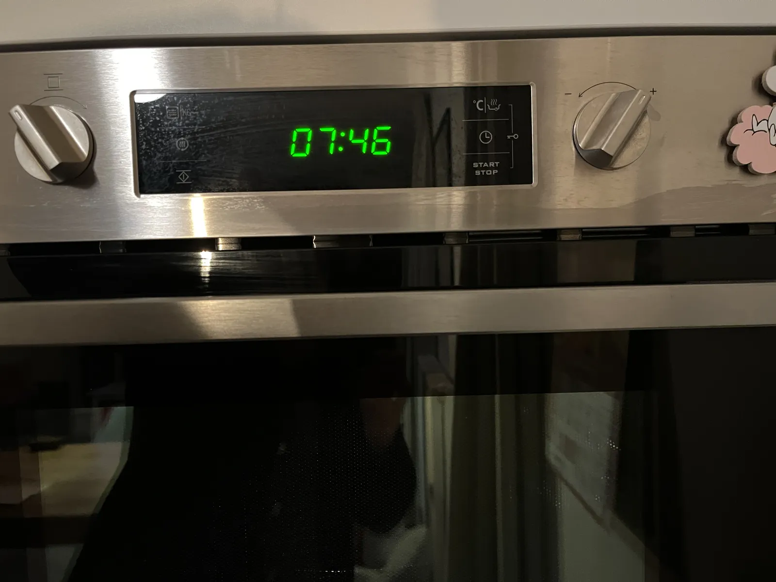 A digital clock on an oven. It displays the time as 07:46