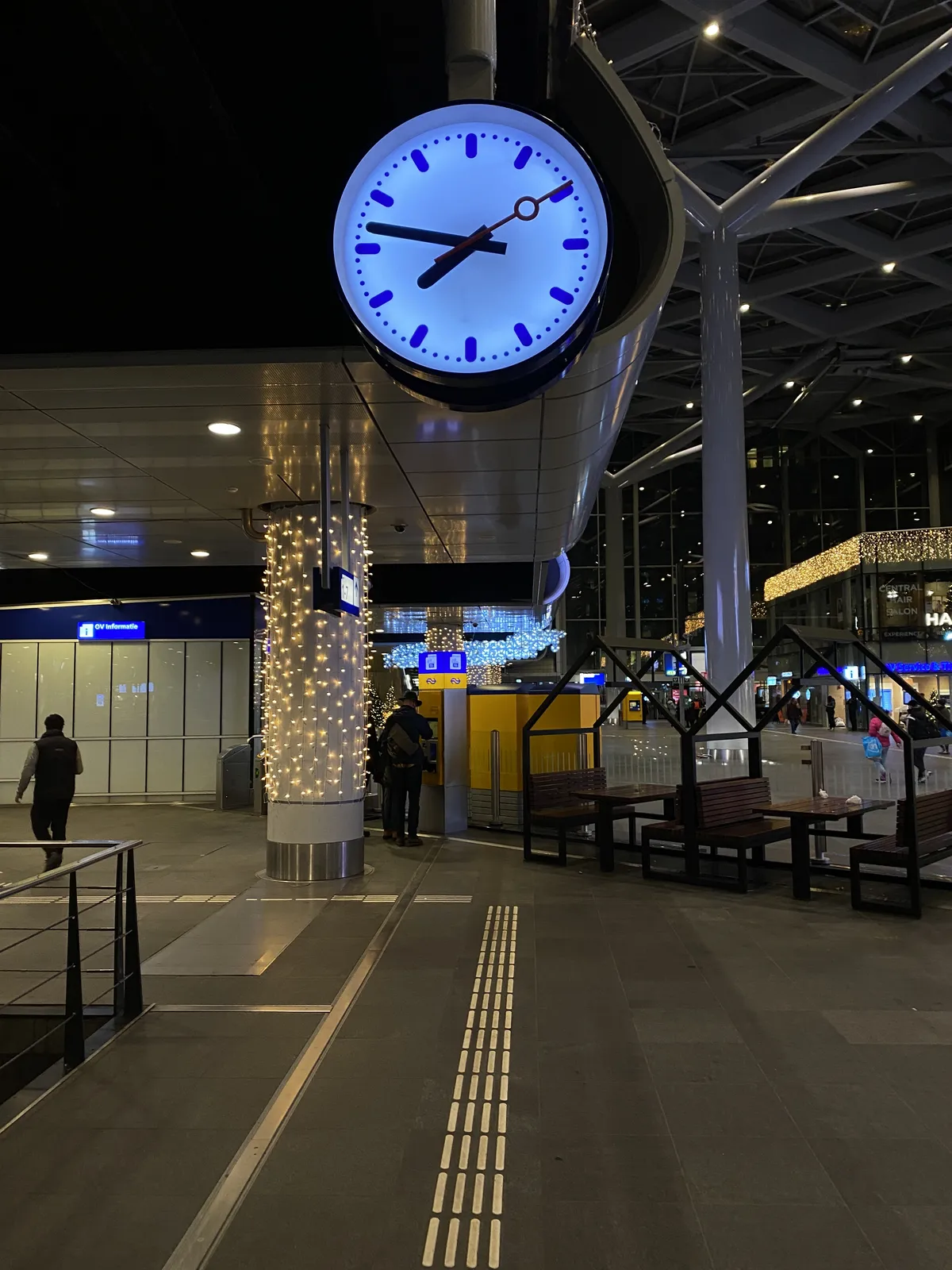 A clock in a Dutch train station. It points at 13 minutes to 8.