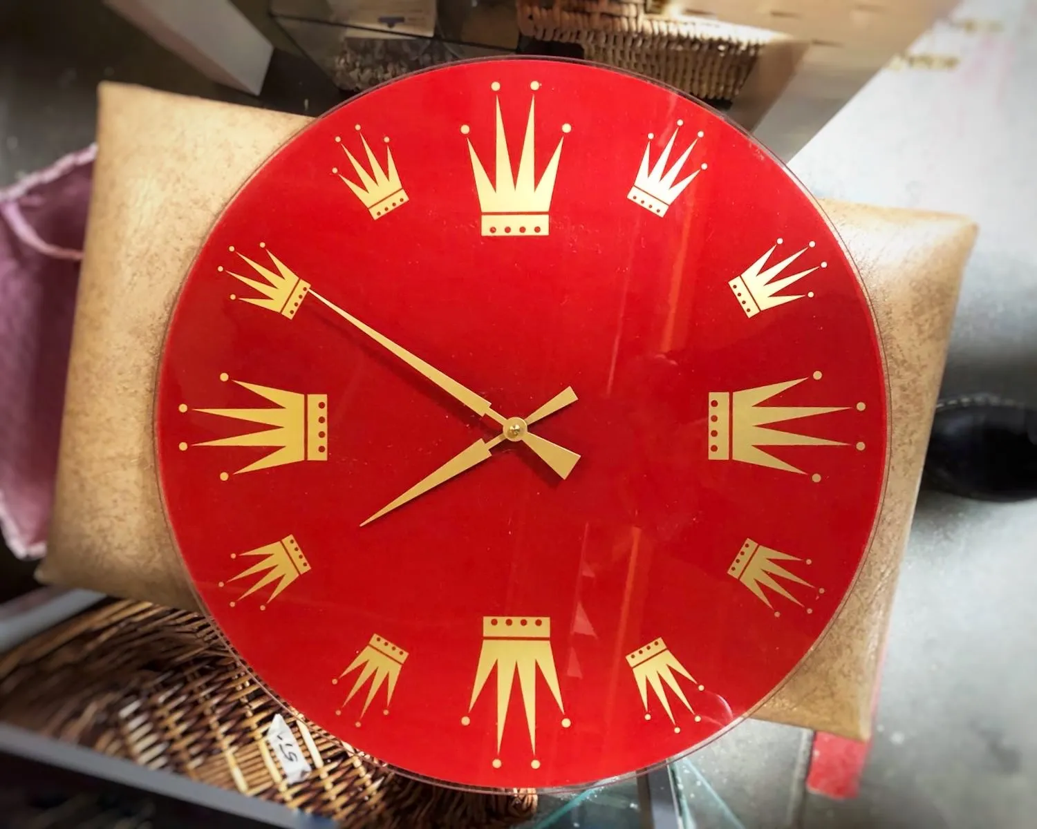 A red clock with golden crowns as hour indicators. It seems to point at 10 minutes to eight.