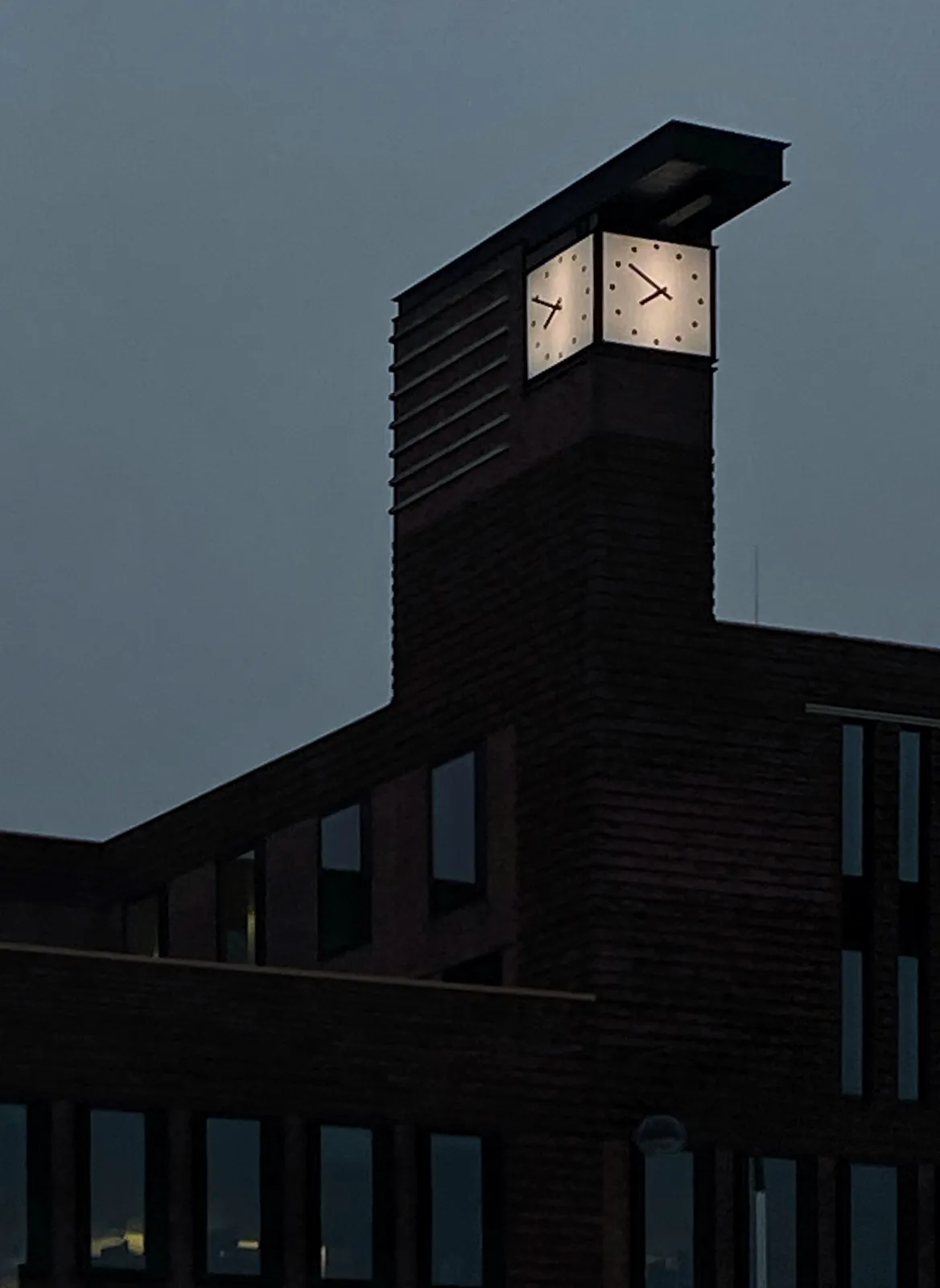 On top of a building which seems to be made out of clocks, there are two aquare clocks. One of them points at 11 minutes to 8, the other at 9 minutes to 8.
