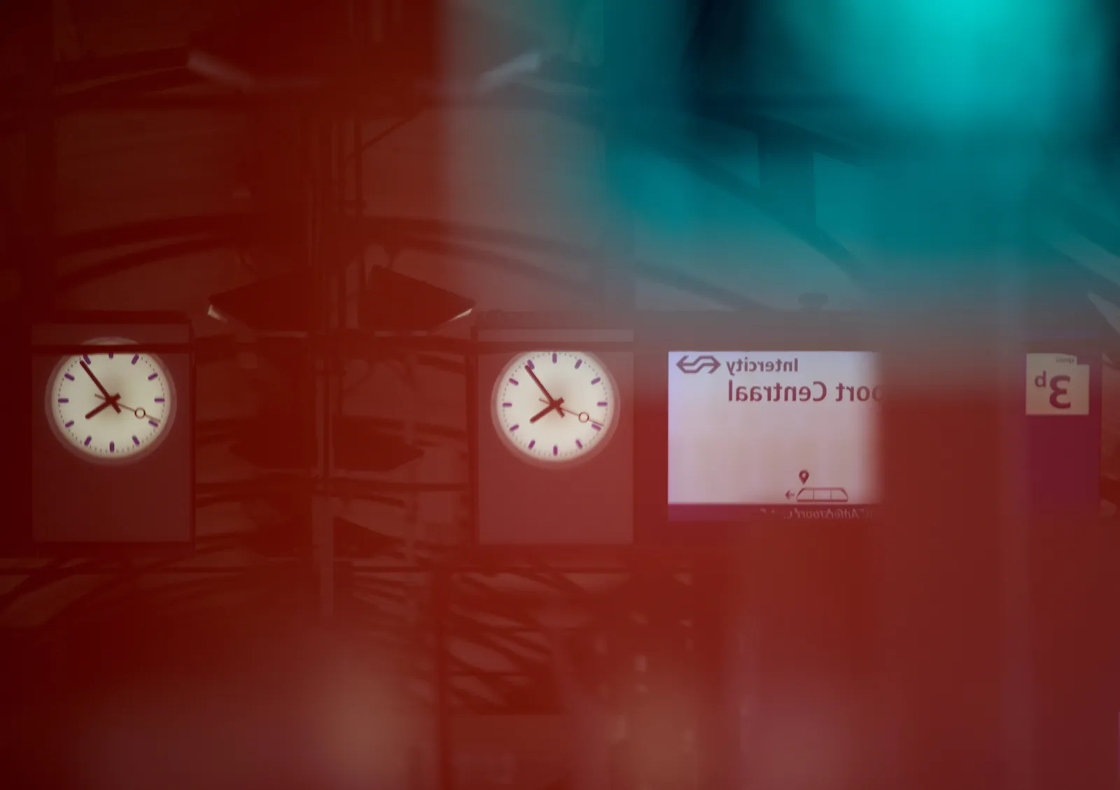 Looking at the mirrored image of two clocks on a train station. They seem to point at 6 minutes to 8.