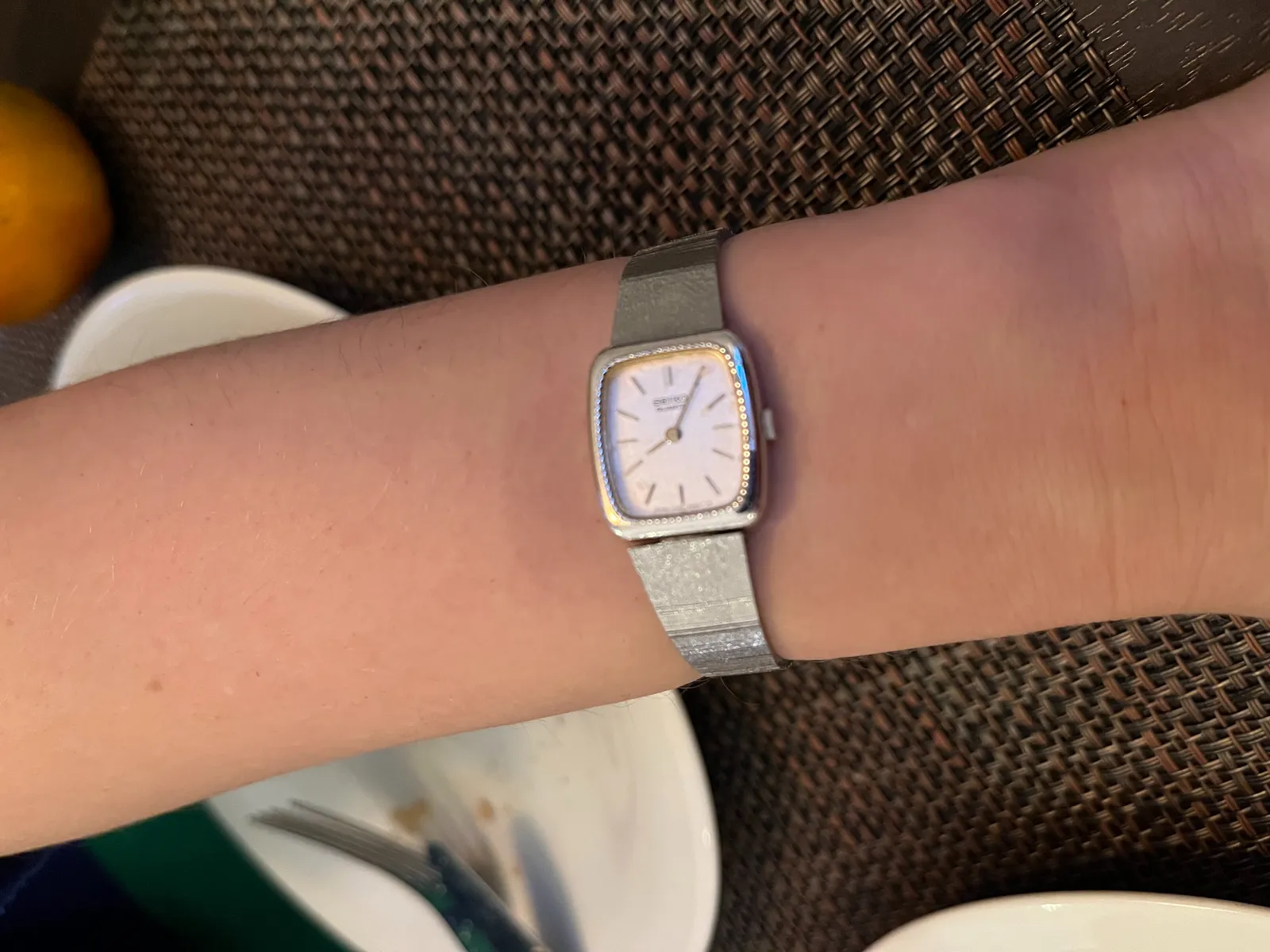 An elegant watch on a wrist. It points at 5 minutes past 8.