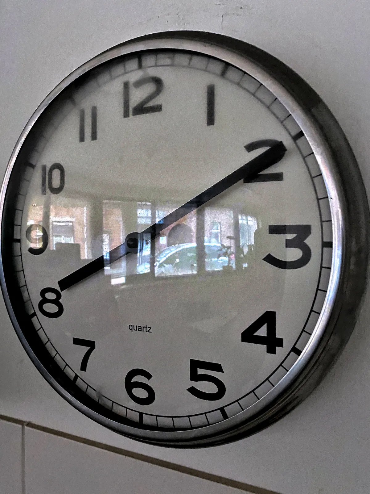 A close-up of a clock on a wall. It points at 10 minutes past 8.